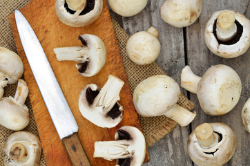 Slicing champignons on a wooden chopping board and sackcloth