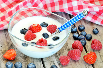 White yogurt in a bowl with blueberries, raspberries and strawberries