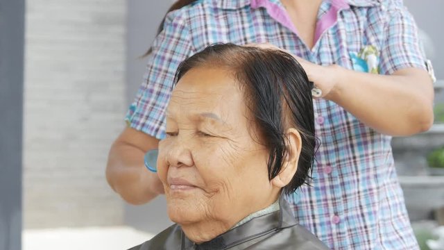 hand of a hairstylist doing a combing hair of senior woman