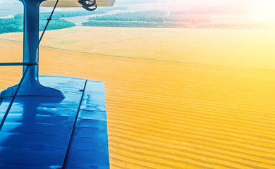A view of the wing of a turboprop aircraft and a field of corn and wheat in the countryside