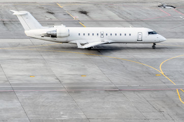 White plane steers for takeoff against the background of the steering tracks