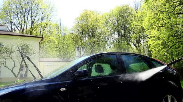 Man washing his car with using a high pressure water jet.