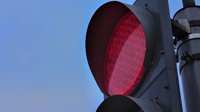 Traffic light changing colors. Red light close-up. Blinking light against sky background.