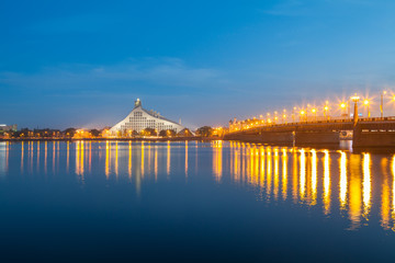 Latvian national library and stone bridge over Daugava river in Riga. Night illuminated scene.