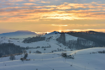Beautiful winter mountain landscape with snowflakes in frosty winter day. Carpathian wild mountains. Romania. Holbav. Bran. Brasov. Romania. Little noise. Colorful winter sky.