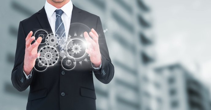 Business man with white cog graphics against blurry building