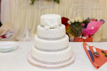 Obraz na płótnie Canvas white wedding cake with a bow on restaurant interior background