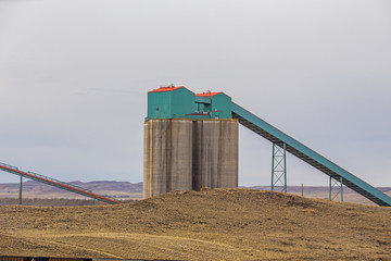 Close up of concrete coal silos and conveyors in a spring Wyoming valley landscape