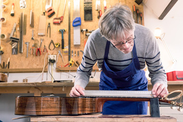 Man measuring the neck of a guitar