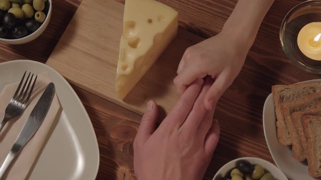 the woman takes the hand of the man on the table is cheese olives