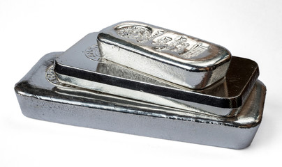 Three silver bars of different weight stacked in a pile.