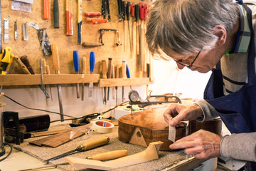 Instrument maker masking a guitar  with tape