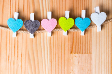 Colorful hearts on twine on natural wooden background.