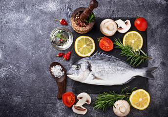 Uncooked dorado fish with rosemary and vegetables