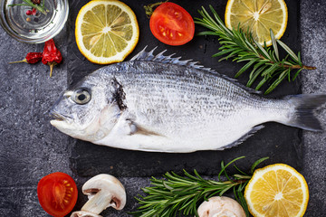 Uncooked dorado fish with rosemary and vegetables
