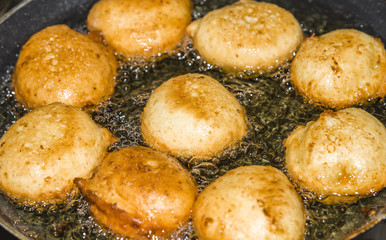 Donuts frying in deep fat. Preparation of traditional donuts