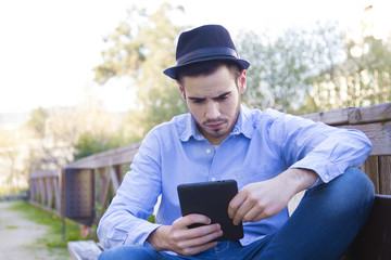 Fototapeta premium young man modern hipster with the tablet or ebook outdoors
