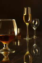 Two glasses of brandy or cognac and bottle on black background