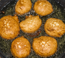 Donuts frying in deep fat. Preparation of traditional donuts