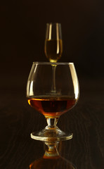 Two glasses of brandy or cognac and bottle on black background