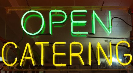 Obraz premium Open and catering neon advertising sign in the window of a restaurant 