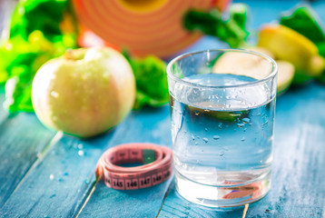 Yoga mat, water fruits and vegetables on a wooden background.