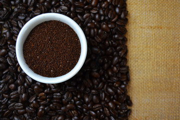 Ground coffee in white cup with coffee beans