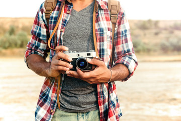 Man in plaid shirt holding old vintage photo camera - Powered by Adobe