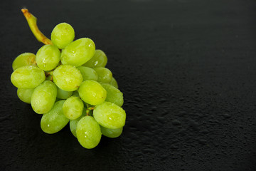 wet green grapes on black slate
