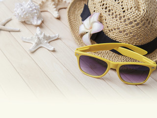 Straw hat and sunglasses on wooden boards.