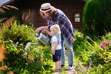 Toddler boy and his young mother watering plants in the garden