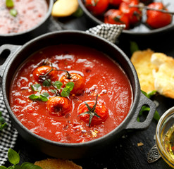 Tomato soup with roasted tomatoes, top view, black background