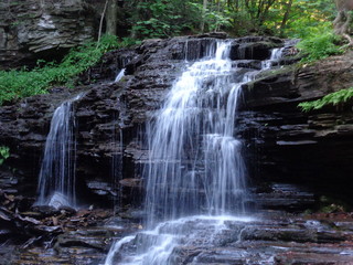 Fototapeta premium Scenic little waterfall flowing over a high rocky mound.