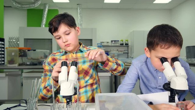 Elementary age boys making science experiments in school laboratory. 4K.