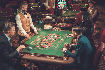 Upper class friends gambling in a casino - obrazy, fototapety, plakaty