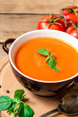 Tomato soup in ceramic bowl on wooden background.