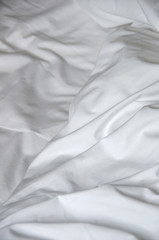 Messy and creased white fabric of bedsheet