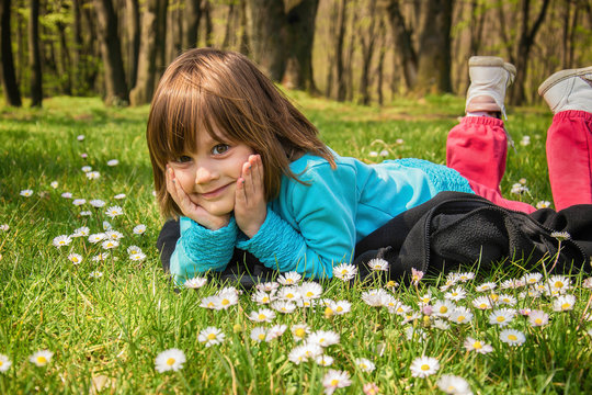 Little girl laying with face on hands in park