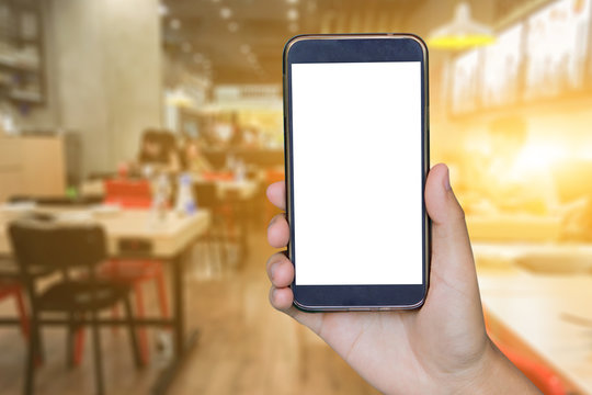 Man hand holding mobile smart phone , tablet,cellphone over Blur or Defocus image of Coffee Shop or Cafeteria,Customer at restaurant blur background with bokeh ,vintage color,food online call shopping