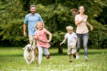 Kinder und Eltern laufen mit dem Hund