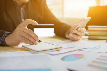 Fototapeta premium man verifies account balance on smartphone with mobile banking application.Online payment,Businessmen's hands holding a credit card and using smart phone for online shopping 