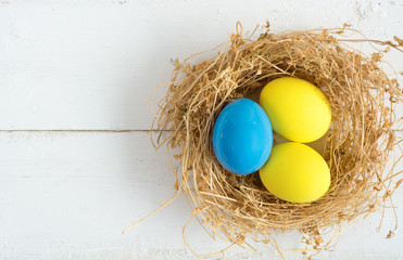 Happy Easter Card - space for text. Easter eggs in nest on rustic wooden background, selective focus image 