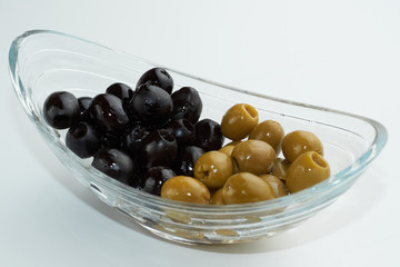 Pickled green and black olives in a glass bowl on white background