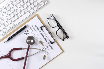 Top view of modern, sterile doctors office desk. Medical accessories on a white background with copy space around products.Workplace of a doctor. Stethoscope, clip board, glasses and other things