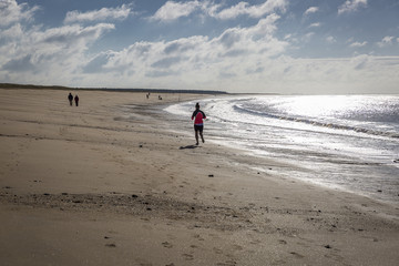sandy beach in Vendee, France with blue sky and white clouds and people wandering