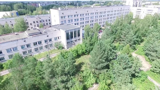 Aerial view over the small town. Aerial survey of buildings and trees. Flying over the yard and over people's heads. Flying over Civil Records Office. Aerial survay of the center of the city.Aerial