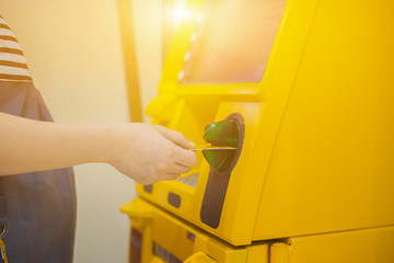 Hand inserting ATM card into bank machine to withdraw money,People stand in a queue to use the ATMs of a bank. Person receiving money from the ATM.vintage color..