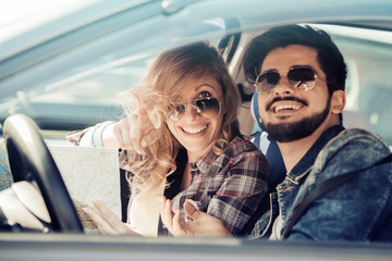 Smiling man and woman using map on roadtrip