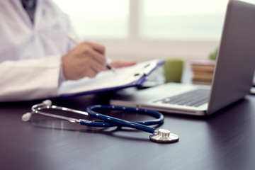 Stethoscope with clipboard and Laptop on desk. Stethoscope on a prescription,Doctor working a Medical Exam, Healthcare and medically concept,test results in background,vintage color,selective focus