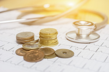 Coins money with medical expenses label, financial concept. Vintage color wooden background with dramatic light.Cost of health care concept, stethoscope and calculator on document, in the savings,..